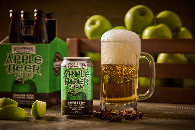 SodaBeers Brewing Company Apple Beer Five can with a glass of Apple Beer and apples in the background.