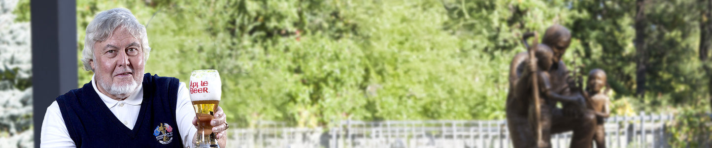 Man holding a SodaBeers mug outdoors with greenery in the background